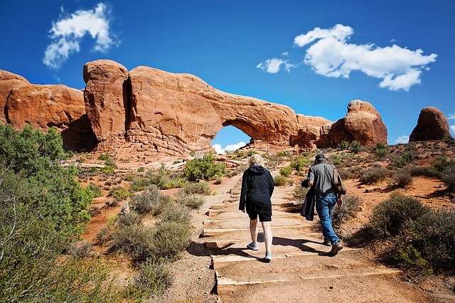 couple hiking to desert arch